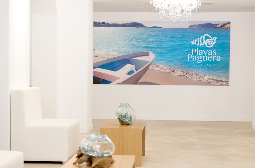 Recepción Detalle de la zona de recepción, con butacas blancas y mesitas de madera