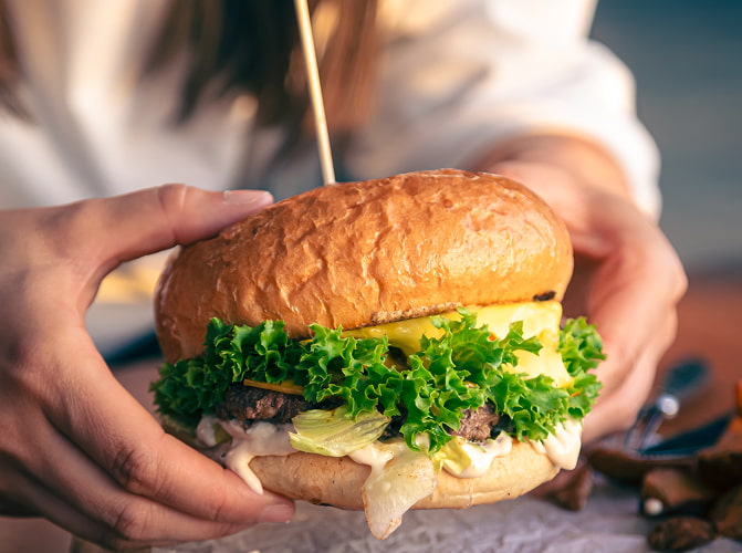 Manos con hamburguesa completa