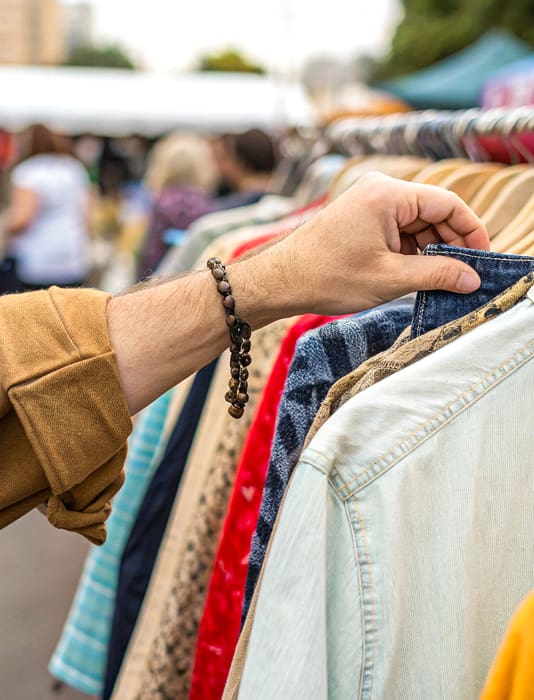 Eine Hand wählt Kleidung von einem Kleiderständer aus