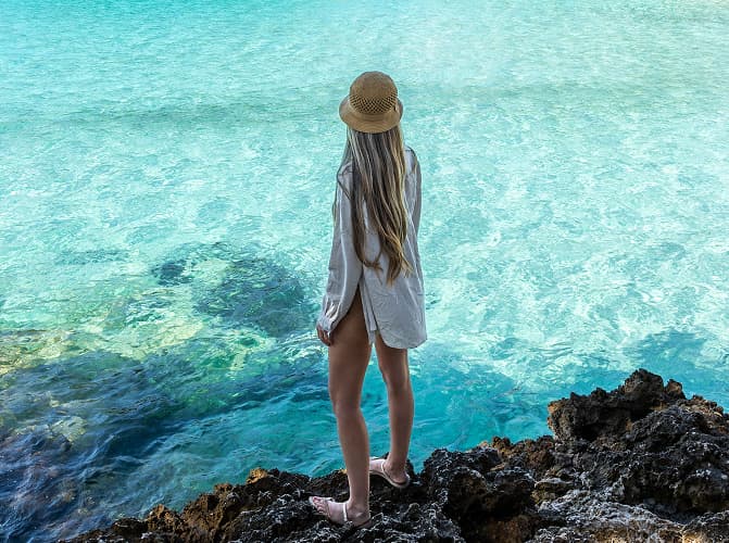 Mädchen auf Felsen mit Blick auf das klare Wasser