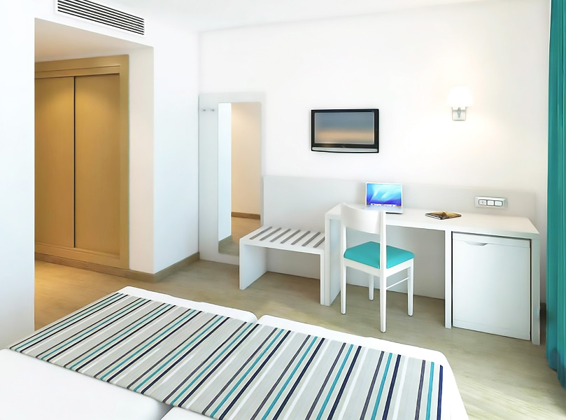 Habitación Doble con Balcón_Escritorio Vista lateral de la habitación, donde se ve el escritorio,el espejo de cuerpo entero, mini nevera y TV colgada en la pared.