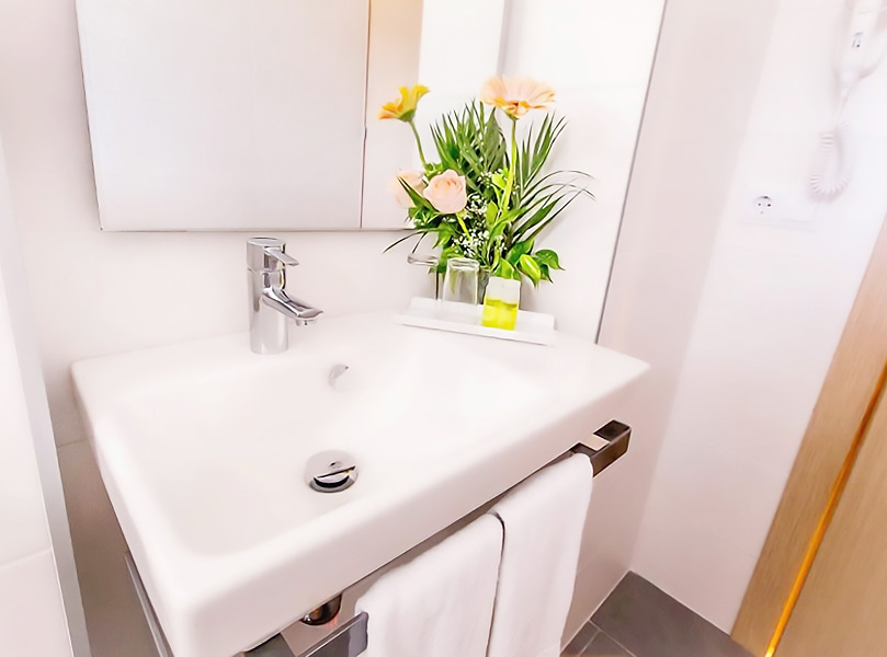 Habitación Doble con Balcón_Lavabo Detalle del lavabo de la habitación, con decoracion floral y dos toallas blancas.