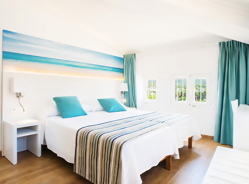 Habitación Doble_General Habitación abuhardillada en color blanco, con detalles azules y con varias ventanas.