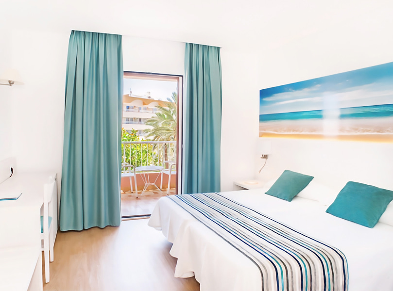 Vista Mar Lateral_Balcón Balcón con mesa y dos sillas, visto desde el interior de la habitación.