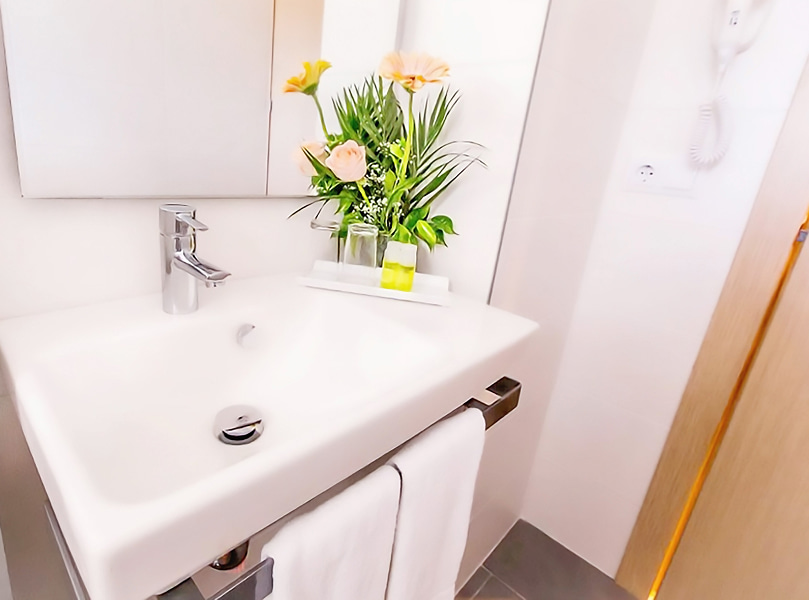 Vista Mar Lateral_Lavabo Detalle del lavabo de la habitación, con decoracion floral y dos toallas blancas.